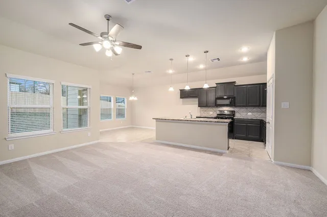 a view of an empty room with a chandelier fan