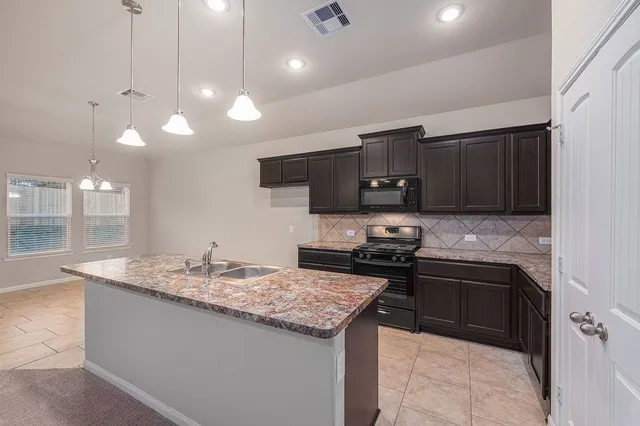 a kitchen with a sink a stove a microwave and wooden cabinets