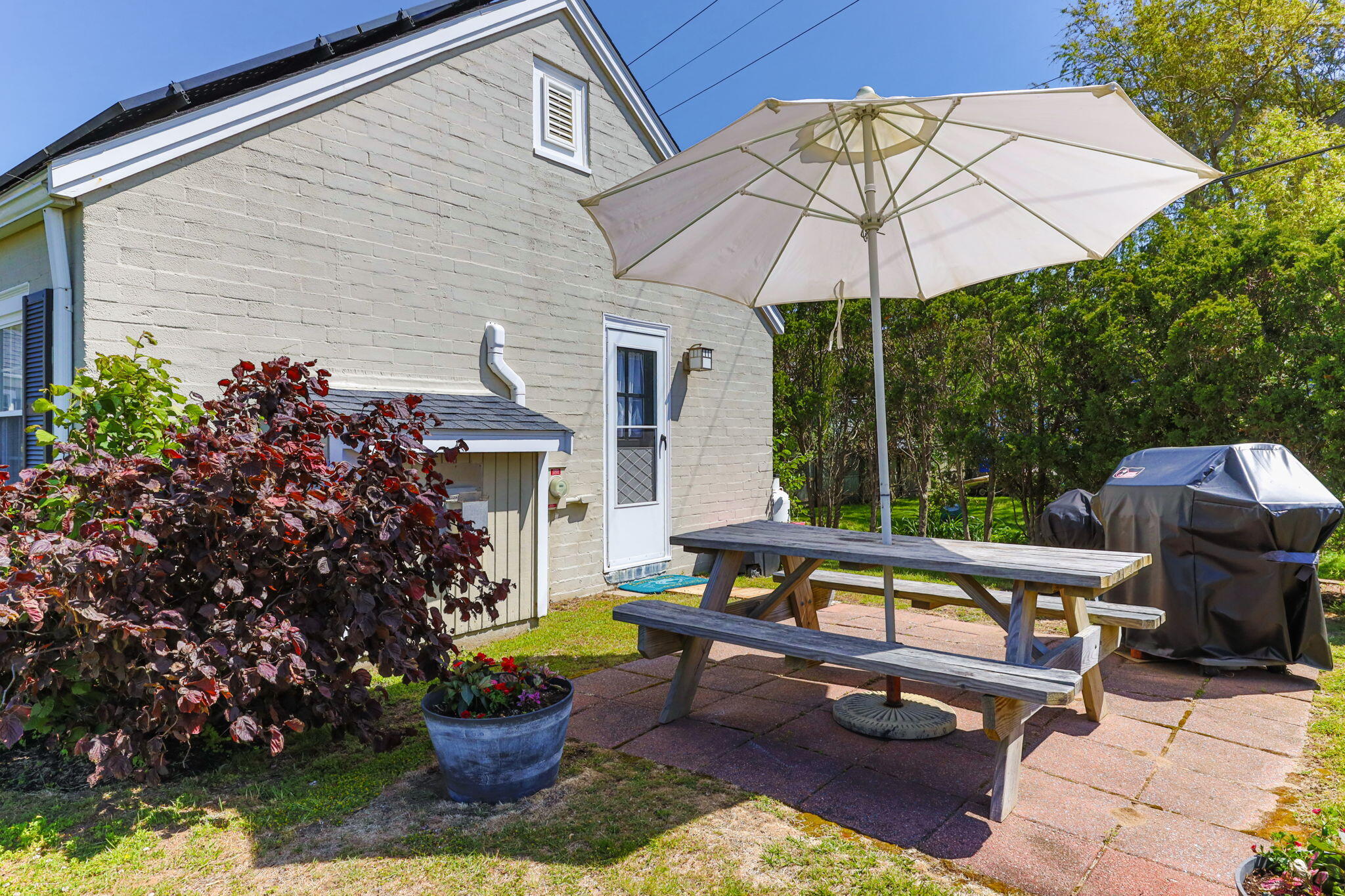 164 Kendrick Avenue, Unit B Wellfleet, MA 02667 - Photo 18 of 32 a view of a patio with a table and chairs under an umbrella