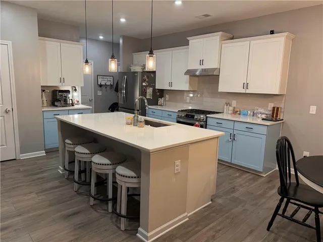 a kitchen that has a lot of cabinets in it and wooden floors