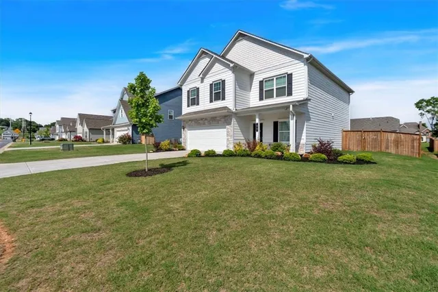 a front view of a house with a garden and trees