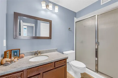 a bathroom with a granite countertop sink toilet and mirror