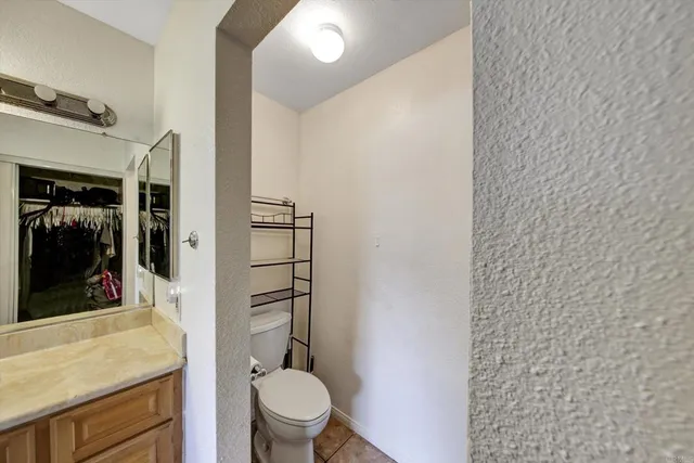 a bathroom with a granite countertop toilet and a sink