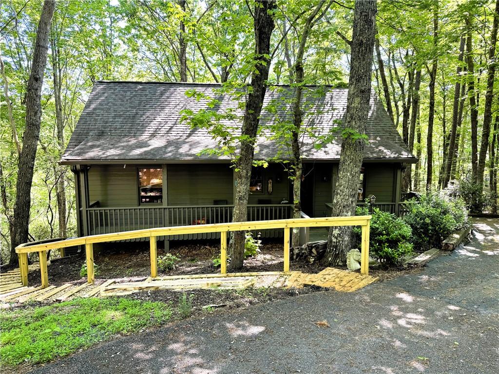 a view of a house with a yard plants and large tree