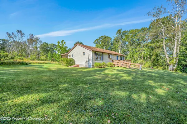 an aerial view of residential house with outdoor space and trees all around