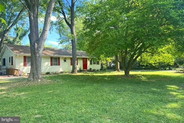 a view of a house with a big yard and large trees