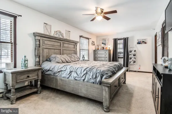 a spacious bedroom with a bed a dresser and a chandelier