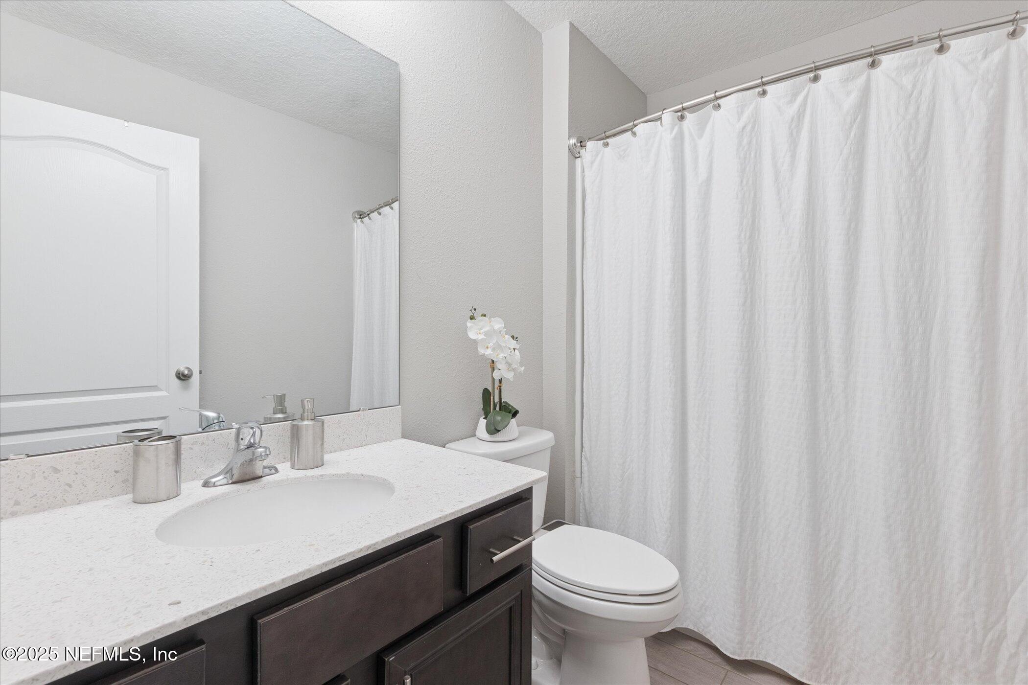 49 Sunberry Way St. Augustine, FL 32092 - Photo 11 of 30 a bathroom with a sink a toilet and shower curtain
