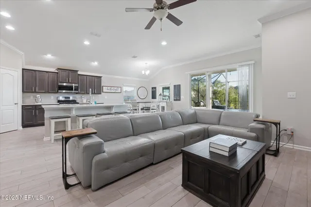 a living room with stainless steel appliances furniture and a kitchen view