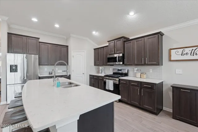 a kitchen with stainless steel appliances a sink a stove a refrigerator cabinets and a center island