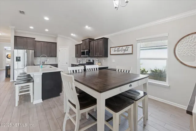 a kitchen with stainless steel appliances kitchen island granite countertop a stove a refrigerator a sink a dining table and chairs