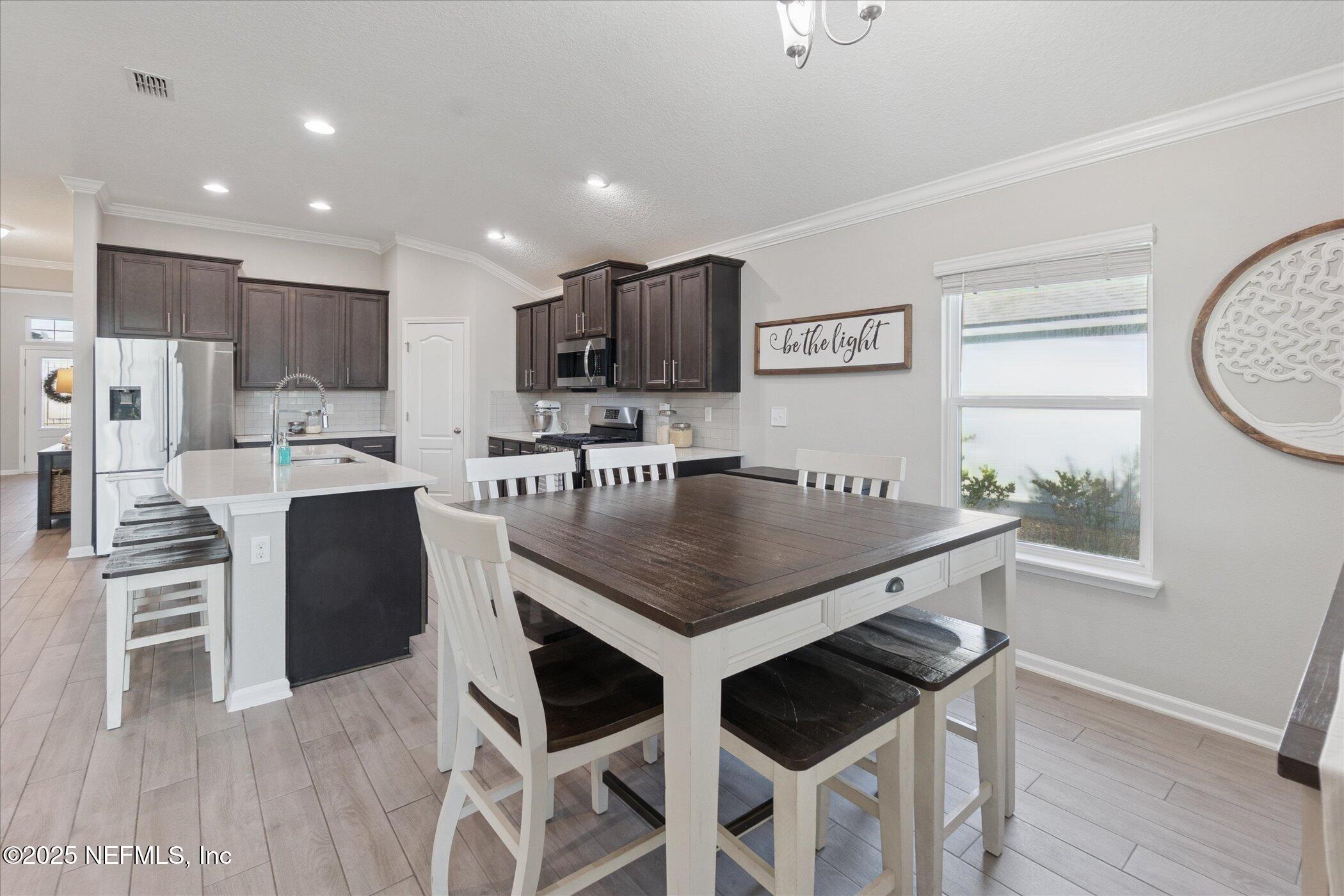 49 Sunberry Way St. Augustine, FL 32092 - Photo 10 of 30 a kitchen with stainless steel appliances kitchen island granite countertop a stove a refrigerator a sink a dining table and chairs