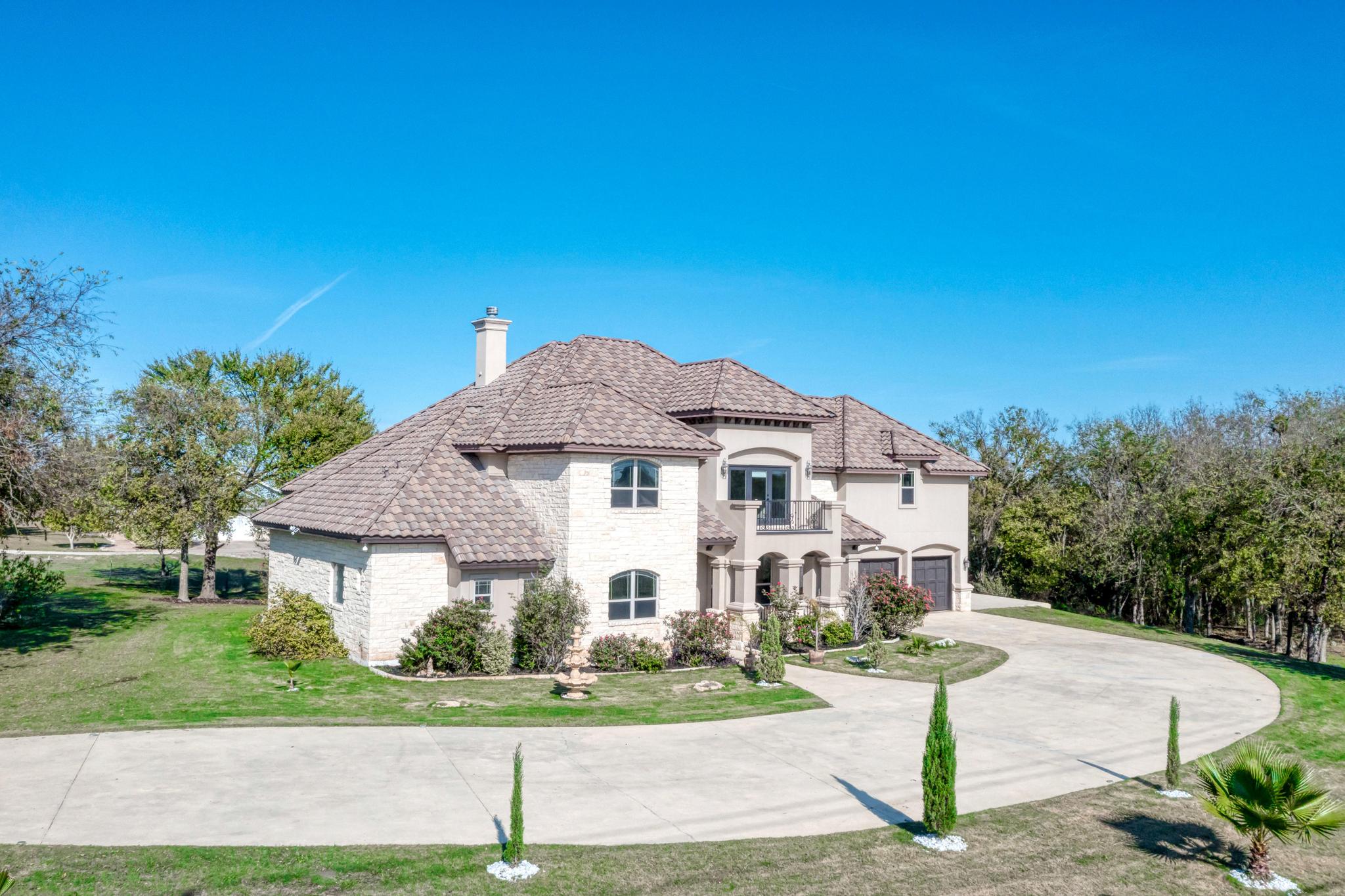 104 Spring Valley Street Hutto, TX 78634 - Photo 2 of 40 View of front of property featuring curved driveway, a tile roof, a front yard, stucco siding, and a chimney