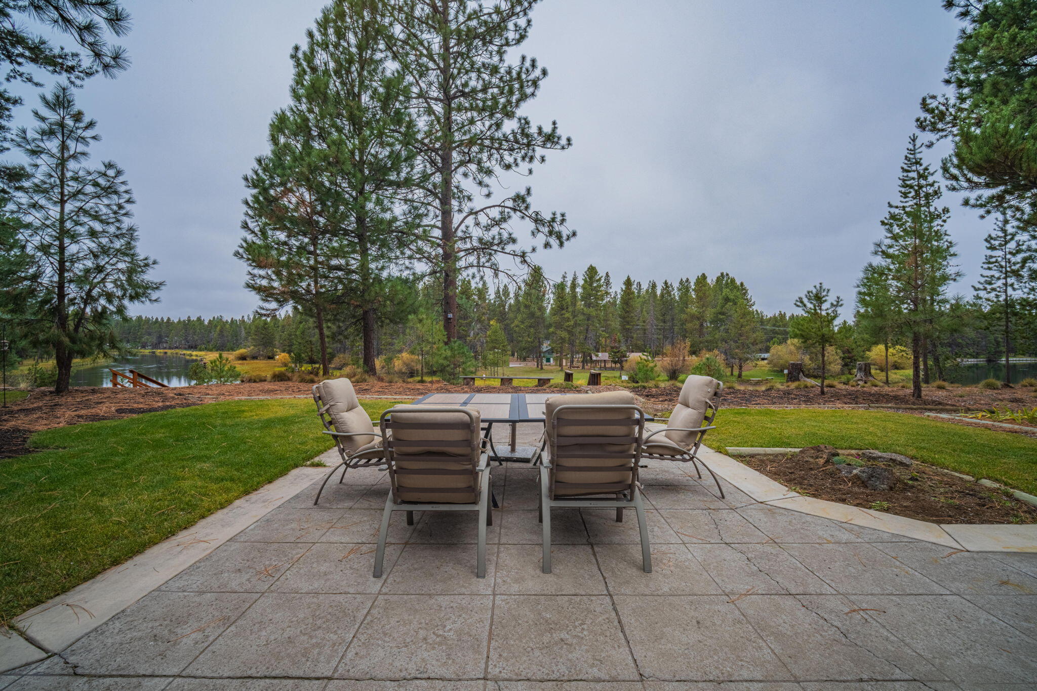 56019 Snow Goose Road Bend, OR 97707 - Photo 11 of 32 a view of a patio with dining table and chairs with a garden