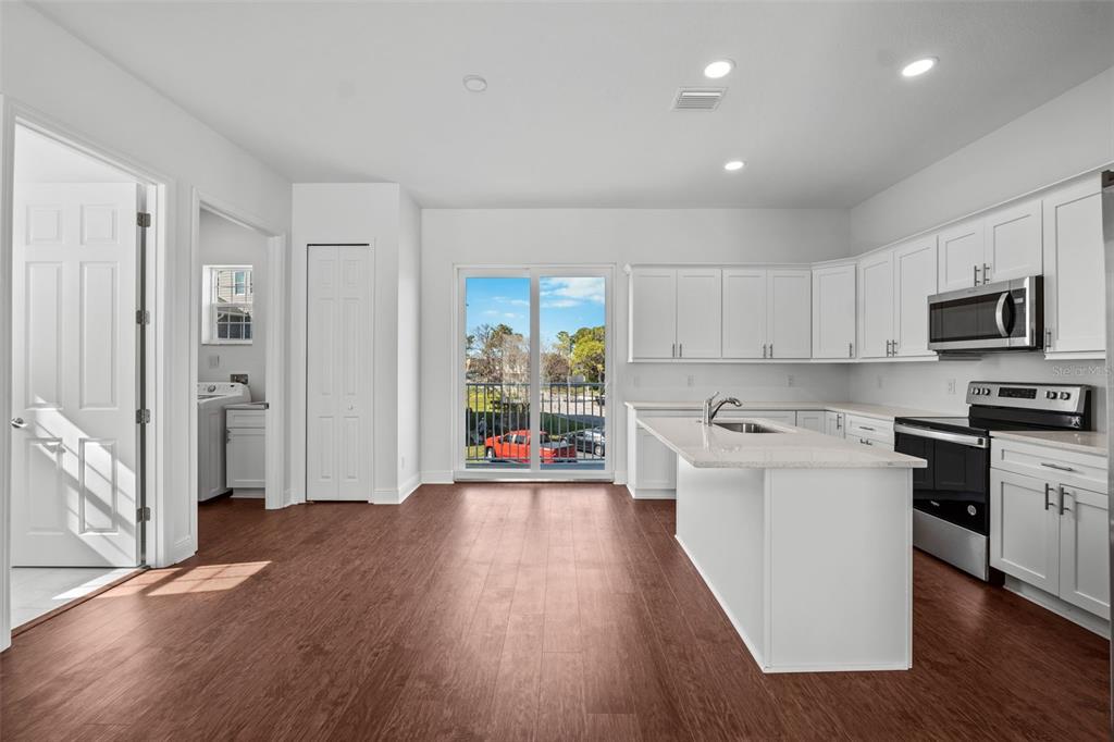 5732 Biscayne Court, Unit 1 New Port Richey, FL 34652 - Photo 6 of 48 a kitchen with stainless steel appliances granite countertop a stove top oven a sink dishwasher a refrigerator and a microwave with wooden floor