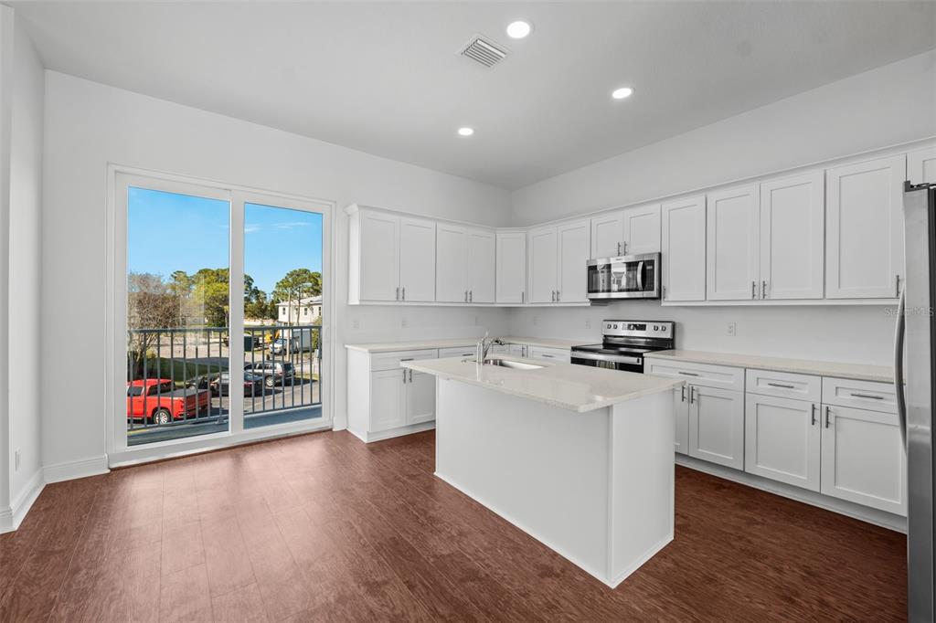 5732 Biscayne Court, Unit 1 New Port Richey, FL 34652 - Photo 7 of 48 a kitchen with stainless steel appliances granite countertop a refrigerator oven a sink dishwasher and white cabinets with wooden floor