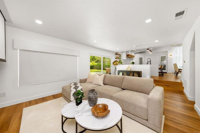 a living room with furniture kitchen view and a wooden floor