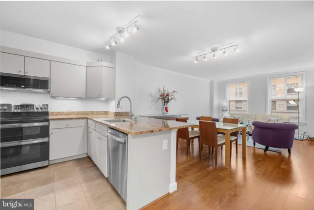 a open kitchen with cabinets a sink dishwasher a stove and a dining table with wooden floor