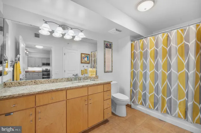a bathroom with a granite countertop sink a toilet and a large mirror