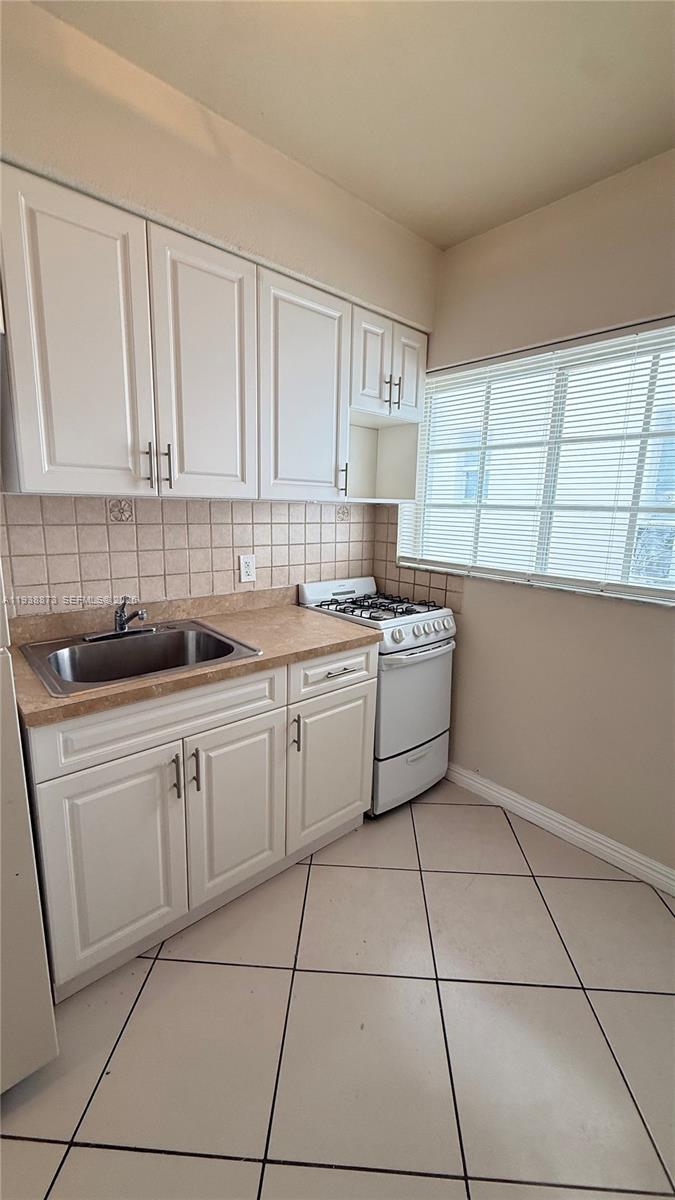 330 74th Street, Unit 16 Miami Beach, FL 33141 - Photo 16 of 22 a kitchen with a sink a stove cabinets and a window