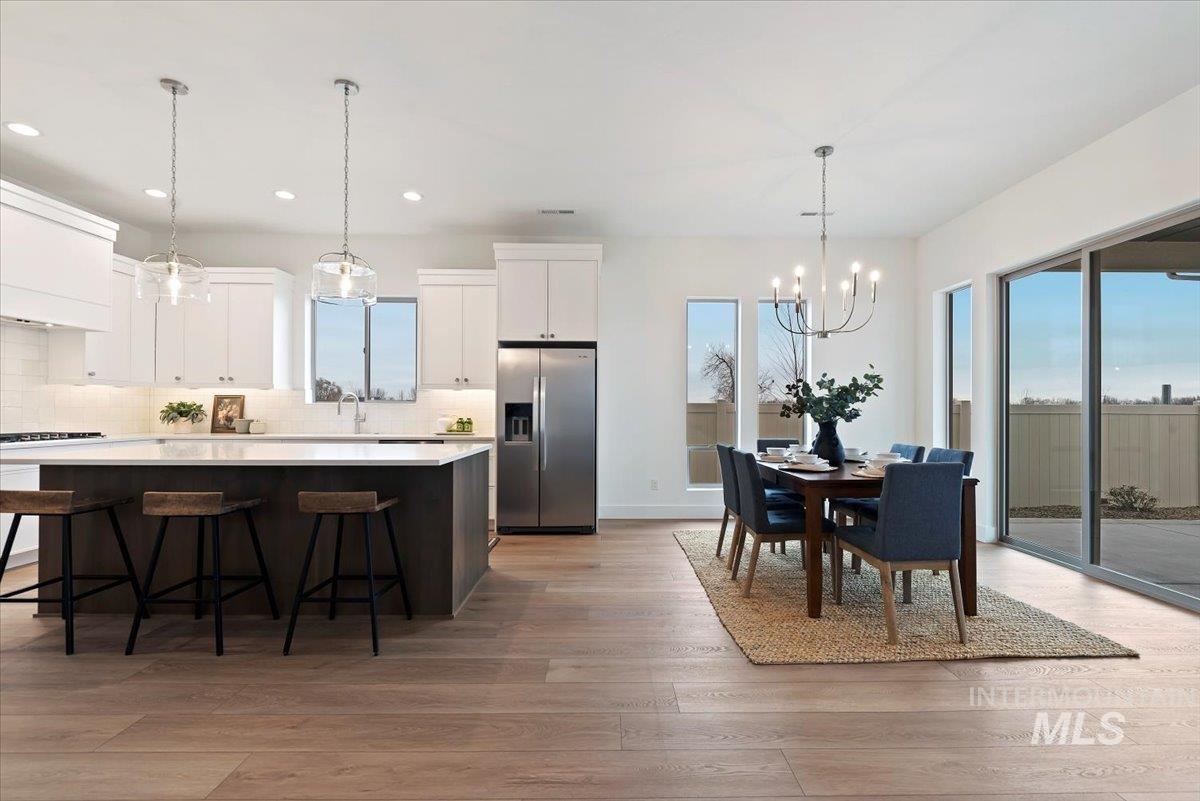 1297 Chena Street Middleton, ID 83644 - Photo 13 of 38 Dual tone kitchen featuring stainless steel fridge, a center island, suspended lighting, a kitchen breakfast bar, and light wood-style floors