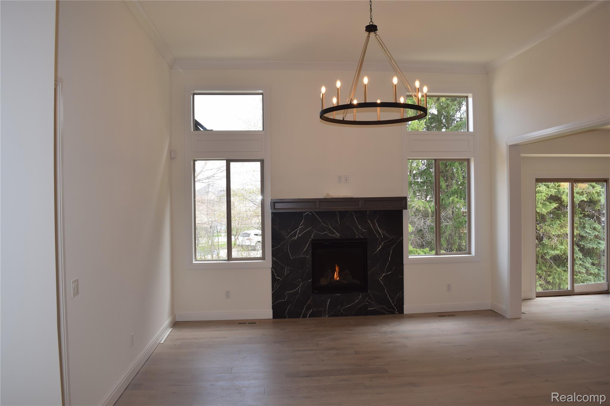 3093 Raffler Drive Rochester, MI 48307 - Photo 25 of 34 Unfurnished living room featuring a premium fireplace, wood finished floors, crown molding, and a chandelier