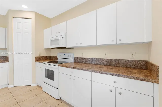 a kitchen with granite countertop white cabinets and white appliances