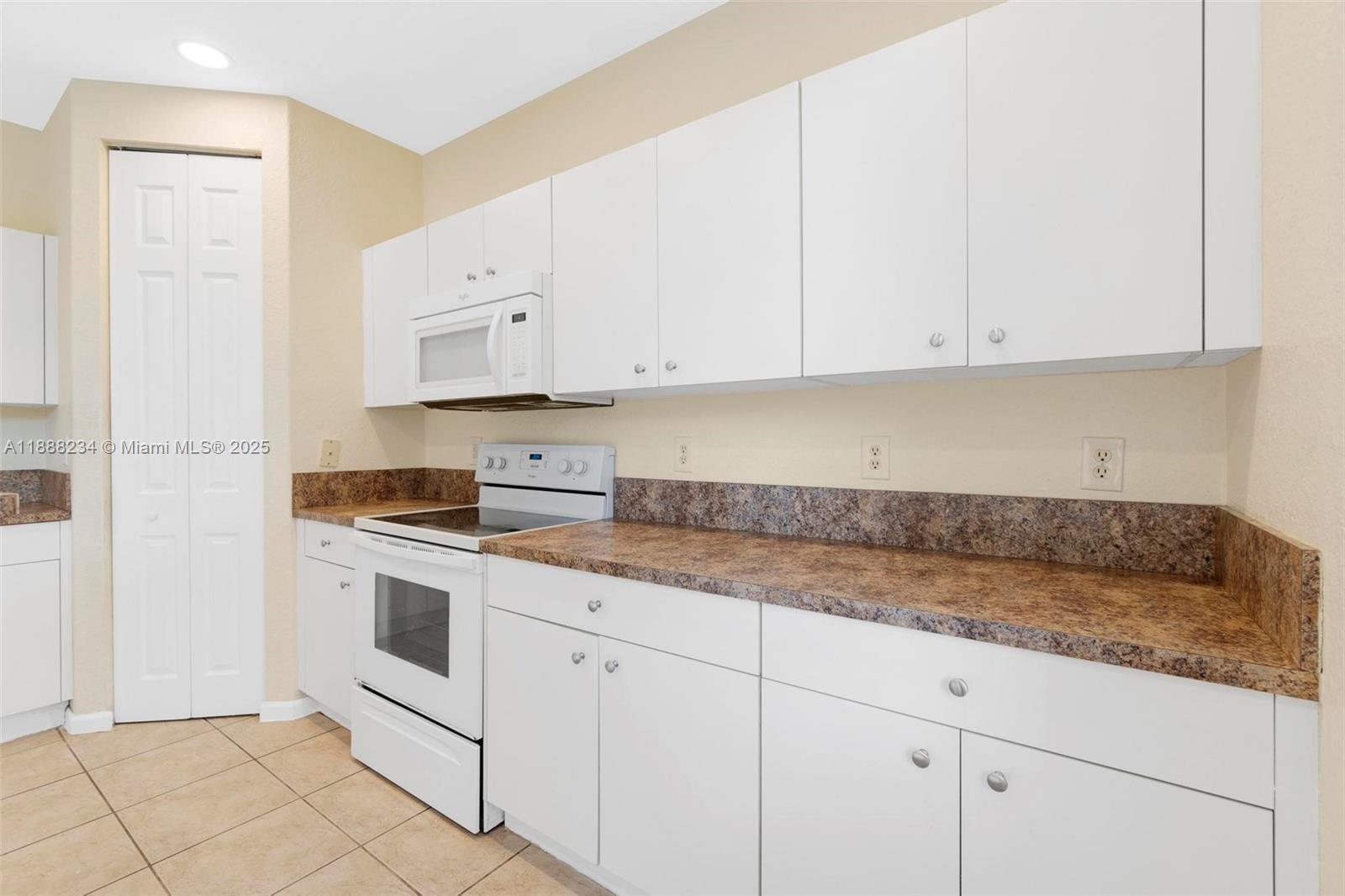 2508 Southwest 85th Terrace, Unit 105 Miramar, FL 33025 - Photo 12 of 27 a kitchen with granite countertop white cabinets and white appliances
