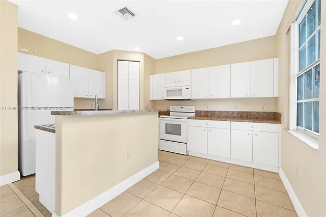 a kitchen with white cabinets and white appliances
