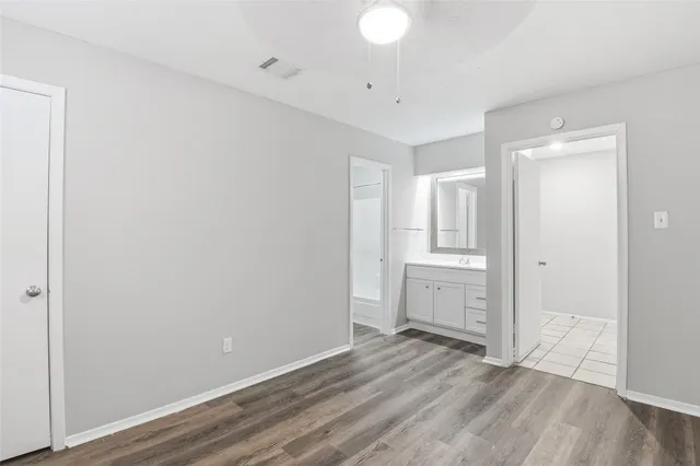 a view of an empty room with wooden floor and closet