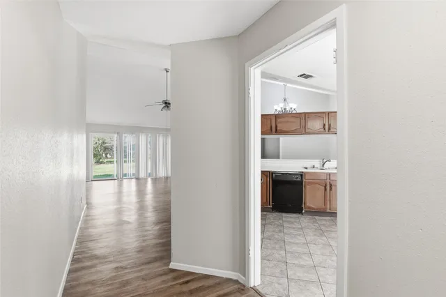 a view of a hallway with wooden floor and a kitchen