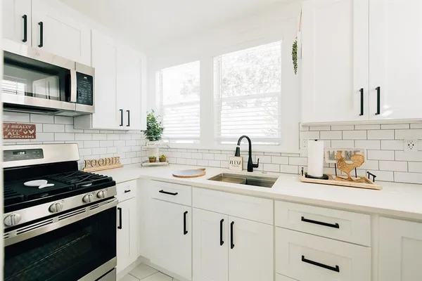 a kitchen with white cabinets and appliances