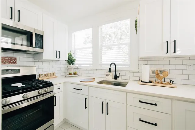 a kitchen with white cabinets and appliances