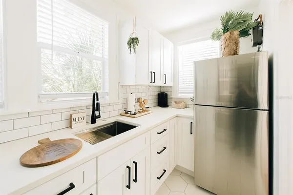 a kitchen with stainless steel appliances a sink a refrigerator and a window