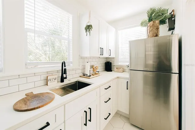 a kitchen with stainless steel appliances a sink a refrigerator and a window