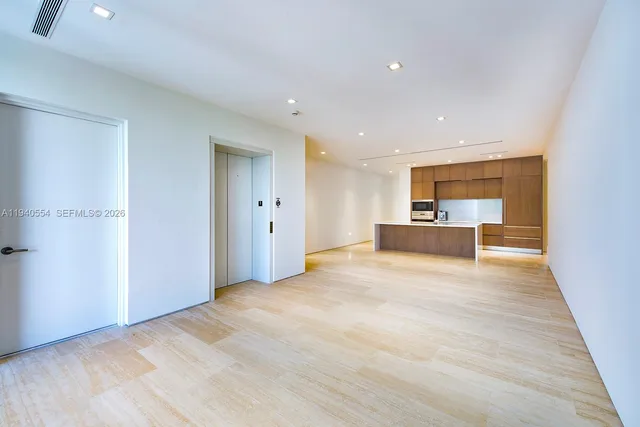 a view of kitchen and empty room with wooden floor and windows