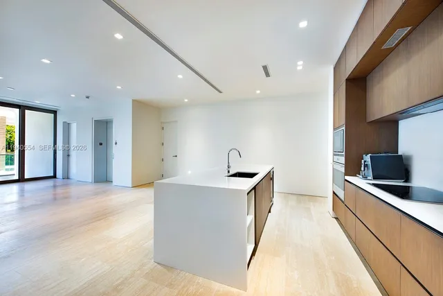 a view of a kitchen with kitchen island a sink wooden floor and stainless steel appliances