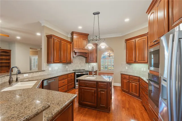 a kitchen with stainless steel appliances granite countertop a sink refrigerator and cabinets