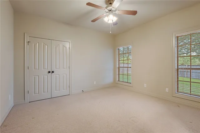 an empty room with a chandelier fan and closet area