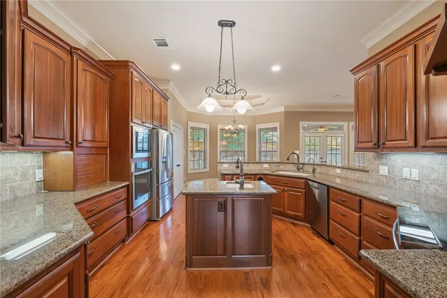 a kitchen with stainless steel appliances granite countertop a sink a stove and a wooden floors