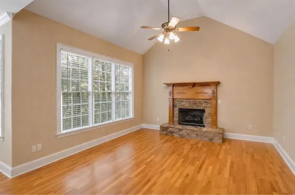 a view of an empty room with wooden floor fireplace and a window