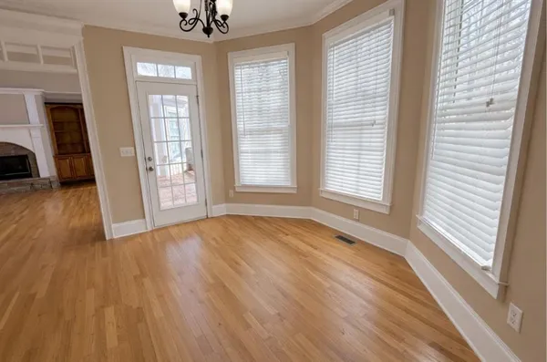 a view of an empty room with a window and wooden floor