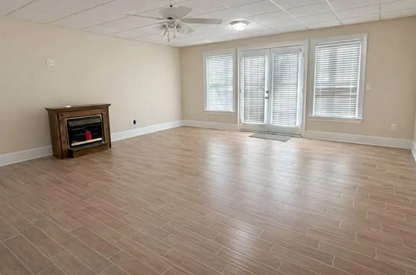 an empty room with wooden floor and windows
