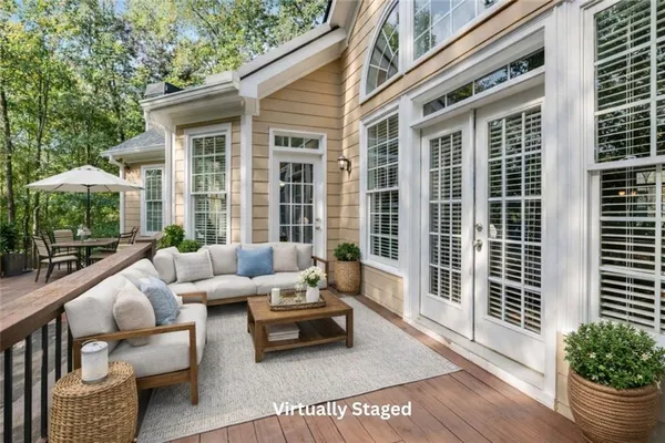 a view of a patio with couches chairs potted plants and floor to ceiling window and wooden floor
