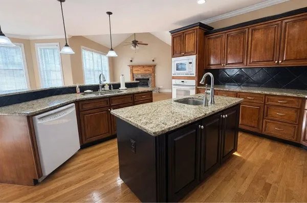 a kitchen with granite countertop kitchen island sink stove and wooden floor