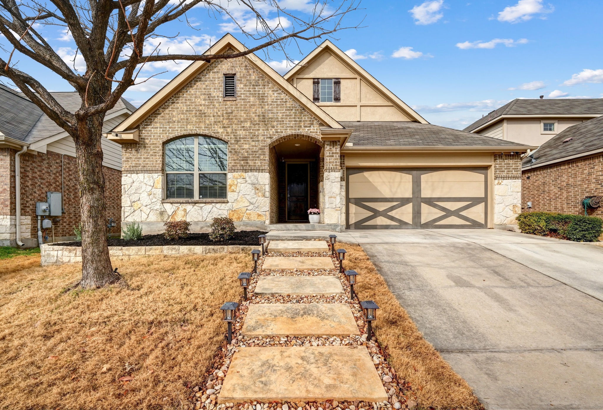 546 Hot Spring Valley Buda, TX 78610 - Photo 1 of 27 View of front of house featuring concrete driveway, an attached garage, stone siding, brick siding, and a shingled roof