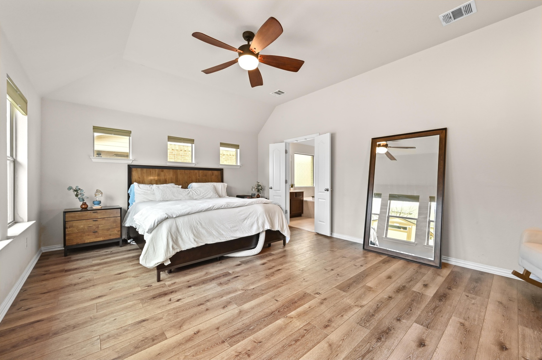 546 Hot Spring Valley Buda, TX 78610 - Photo 15 of 27 Bedroom with light wood-style flooring, connected bathroom, a ceiling fan, and lofted ceiling
