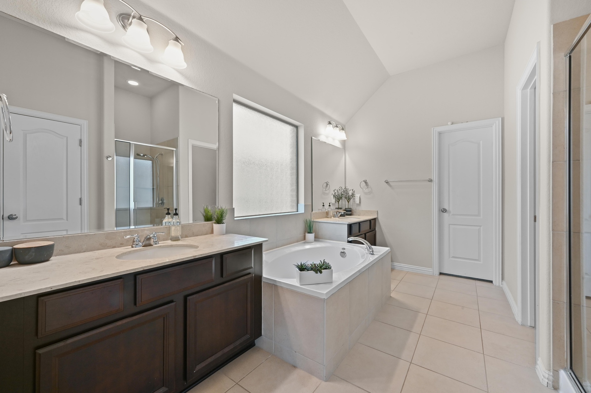 546 Hot Spring Valley Buda, TX 78610 - Photo 18 of 27 Full bath featuring two vanities, a garden tub, a shower stall, light tile patterned floors, and lofted ceiling