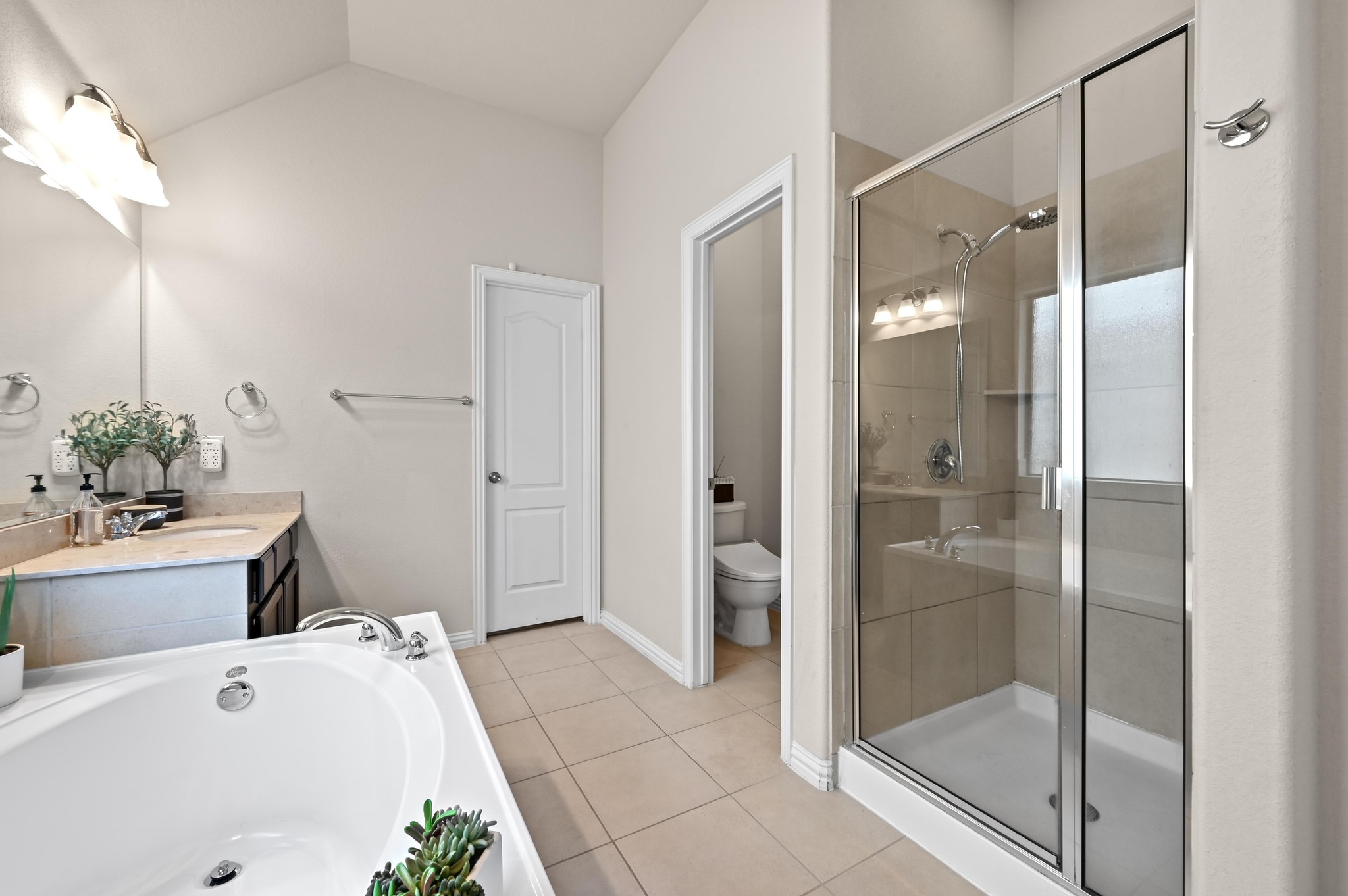 546 Hot Spring Valley Buda, TX 78610 - Photo 19 of 27 Bathroom featuring vanity, a bath, a shower stall, light tile patterned floors, and lofted ceiling