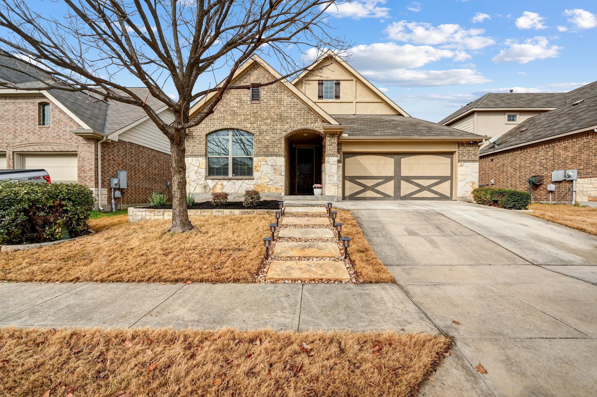 546 Hot Spring Valley Buda, TX 78610 - Photo 2 of 27 View of front of house featuring stone siding, driveway, an attached garage, and a shingled roof